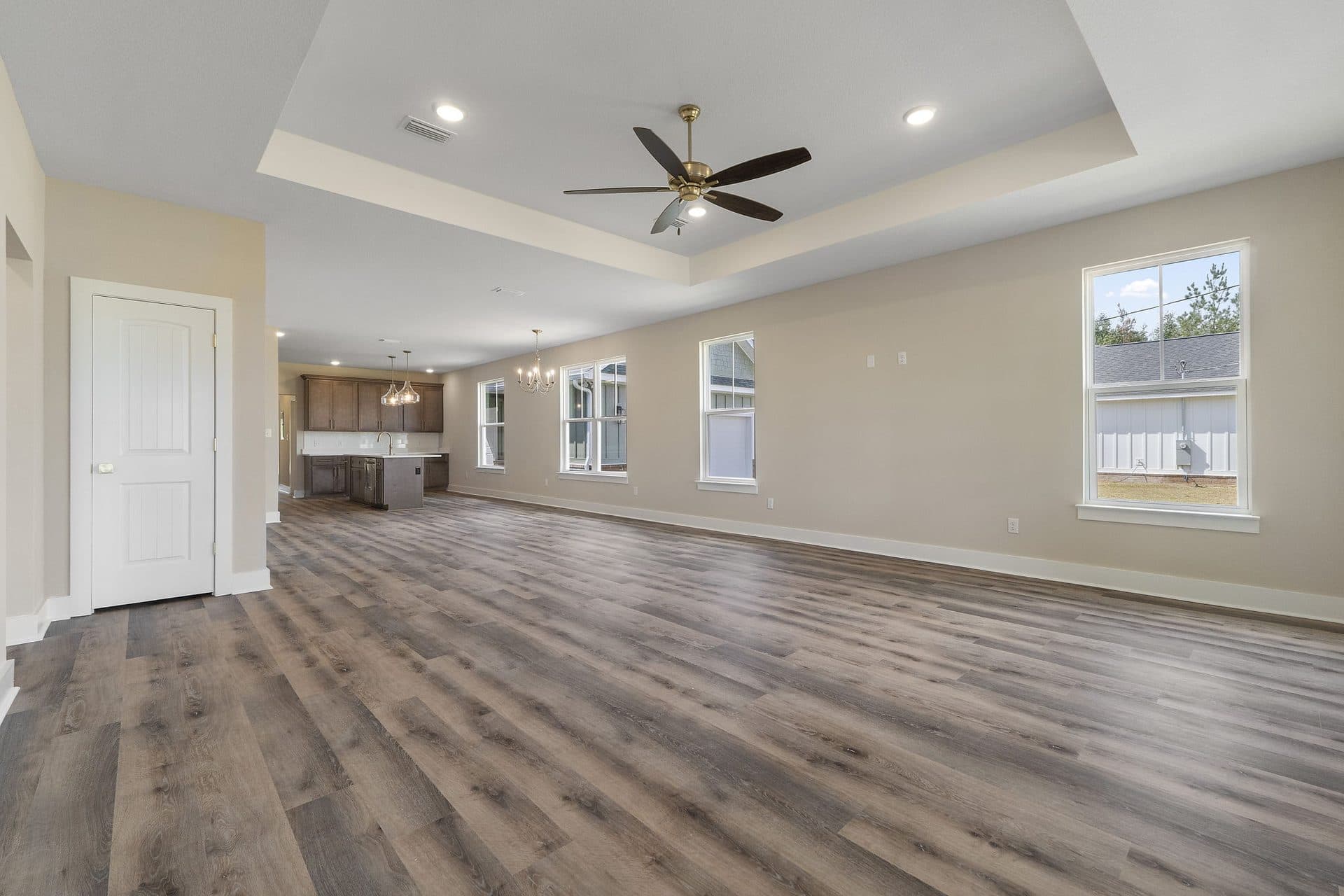 The Ashley great room with a tray ceiling, running back to the kitchen and dining area