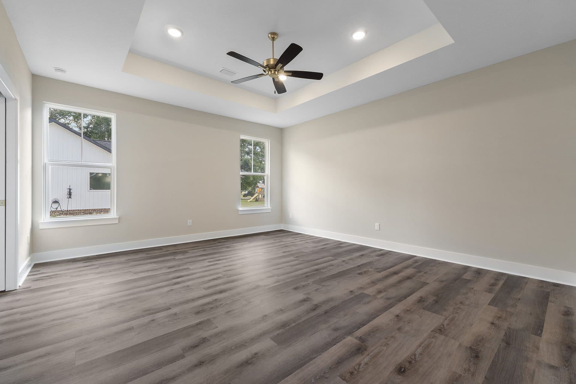 The primary bedroom in The Ashley with a tray ceiling and a ceiling fan