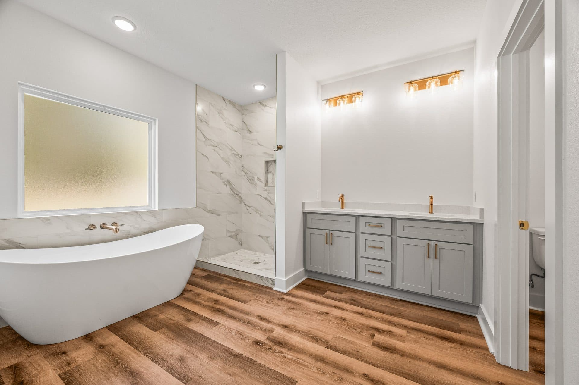 The Cameron primary bath with a freestanding tub, marble-look tile shower and a grey double vanity
