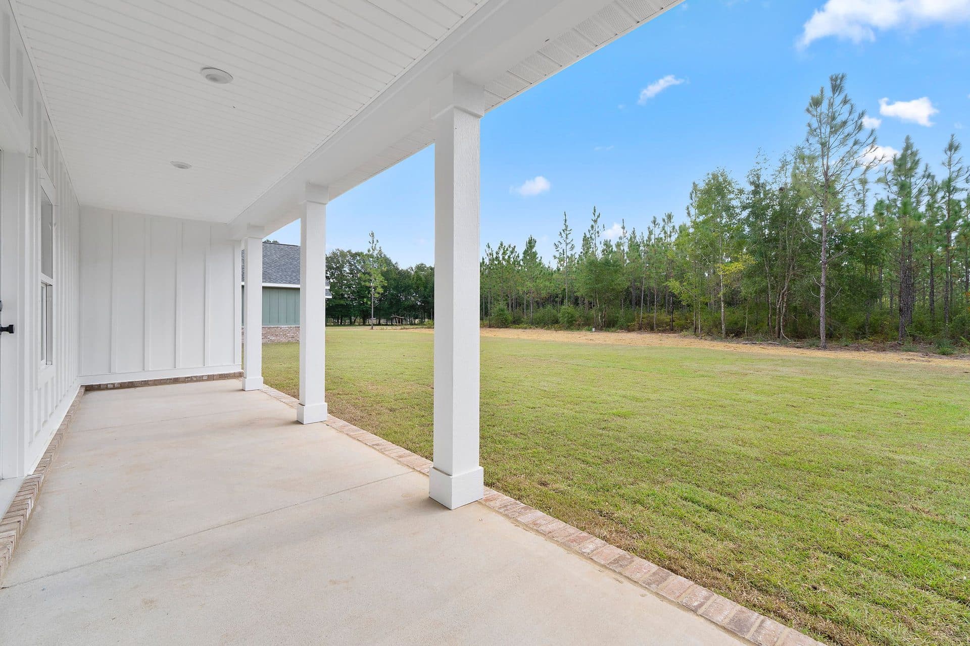 Covered back porch of a finished Lunsford looking out to the tree line