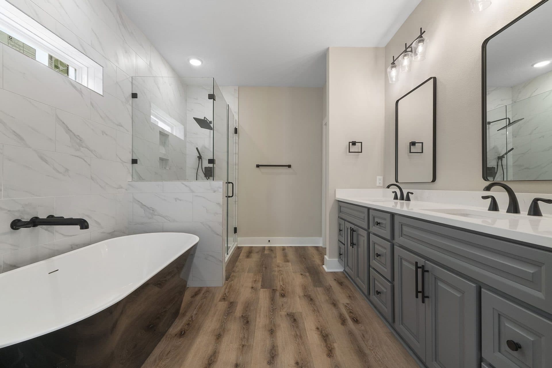 Primary bath of a finished Lunsford with a black freestanding tub and a glass shower